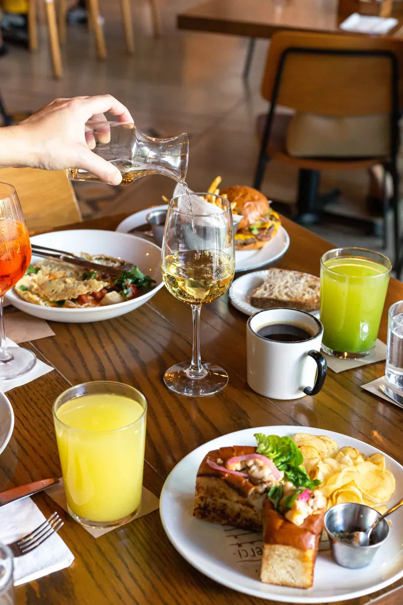 Brunch en Merci: vino blanco servido de la jarra, hamburguesa, jugo verde, jugo de naranja, café y sándwich con chips de la casa