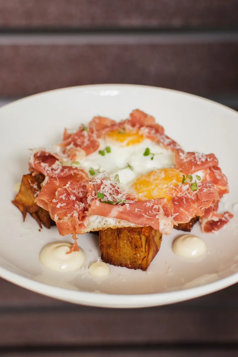 Huevos rotos con mil hojas de papa y jamón Serrano