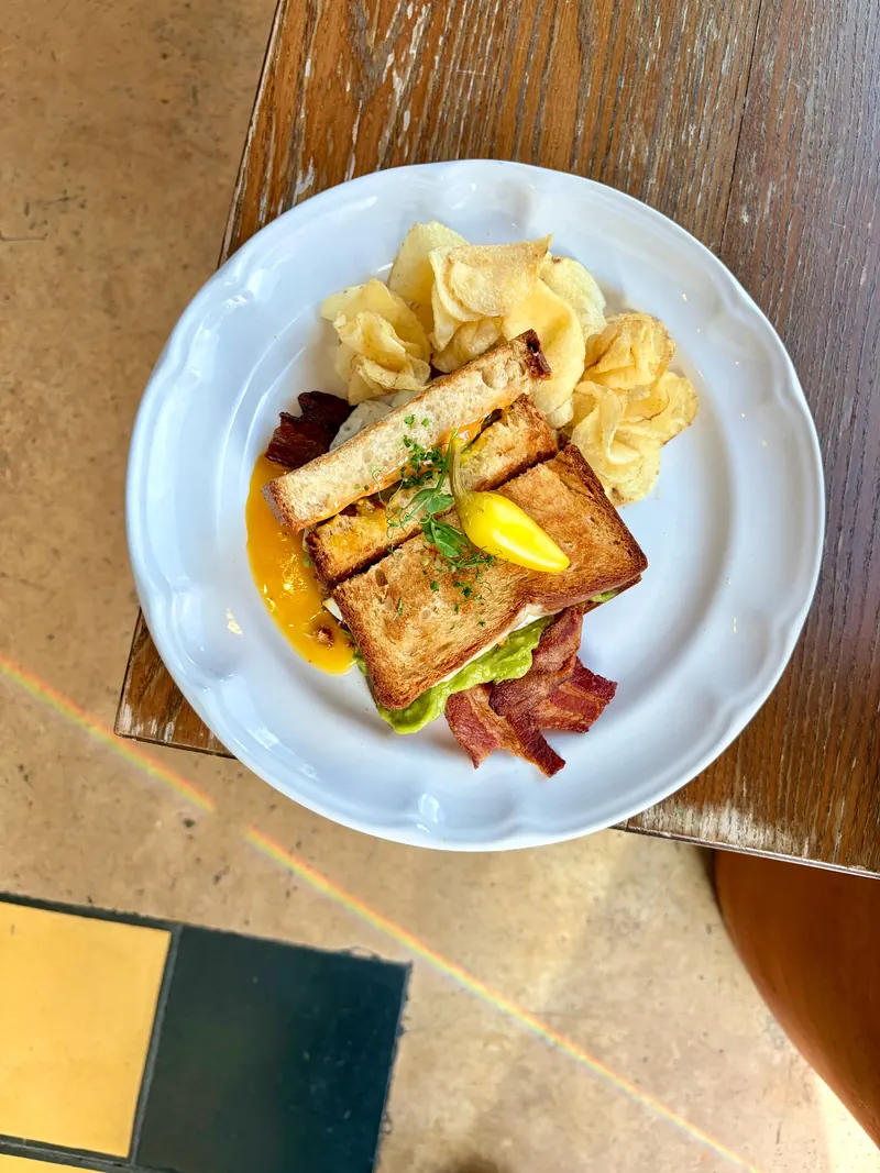 Sándwich Merci con huevo estrellado, tocino y chips de la casa