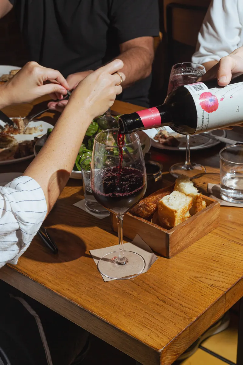 Servicio de vino tinto en la mesa, con pan de masa madre en caja de madera